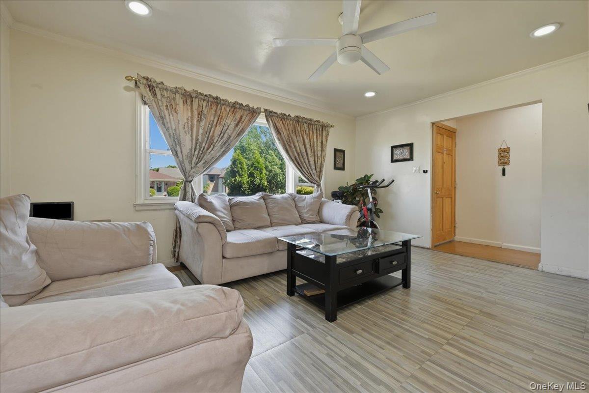 79 Wellington Road Elmont, NY 11003 - Photo 4 of 33 Brightly lit interior space featuring wood-finish flooring, a contemporary ceiling fan, recessed lighting, and crown molding
