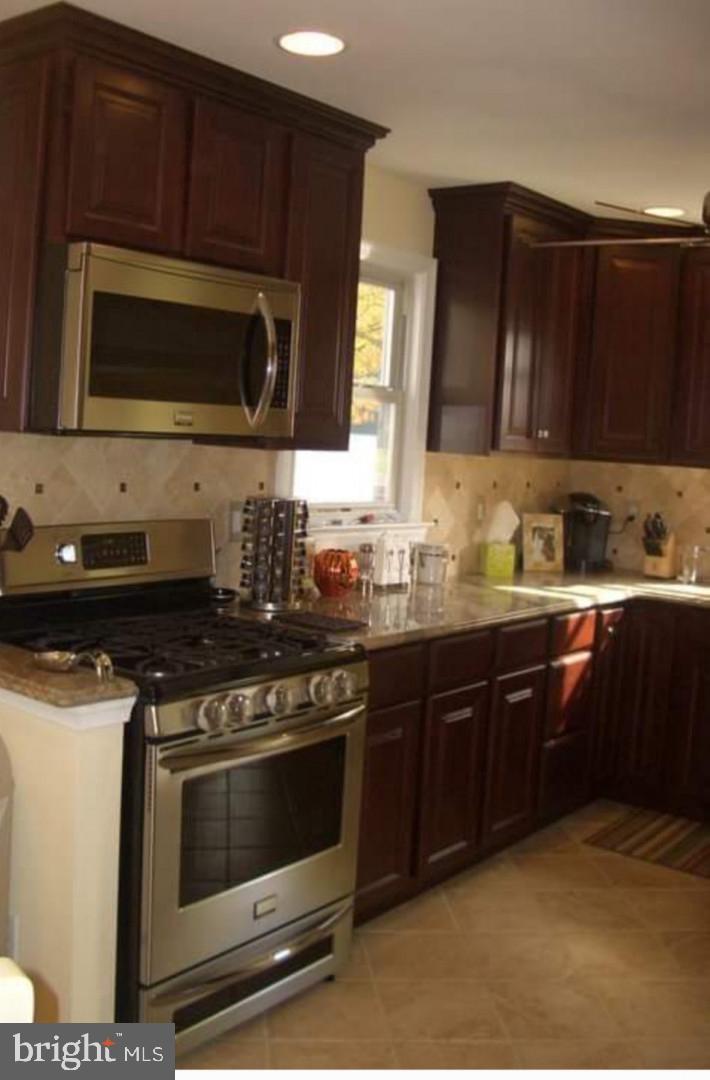 643 Etra Road East Windsor, NJ 08520 - Photo 5 of 26 a kitchen with stainless steel appliances a stove a microwave a sink and cabinets