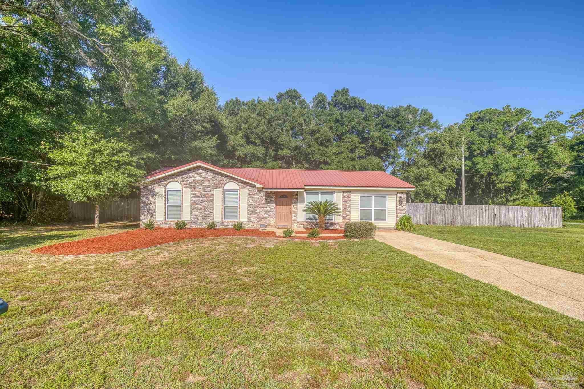 a view of a house with a yard and a large tree