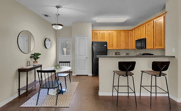 a kitchen with stainless steel appliances granite countertop a table chairs refrigerator and cabinets