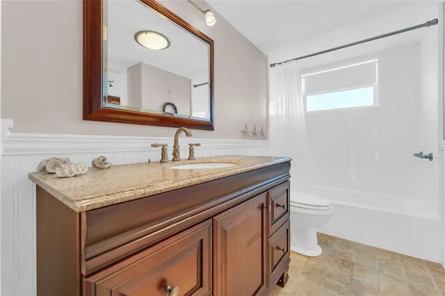 a bathroom with a granite countertop sink a toilet a mirror and shower