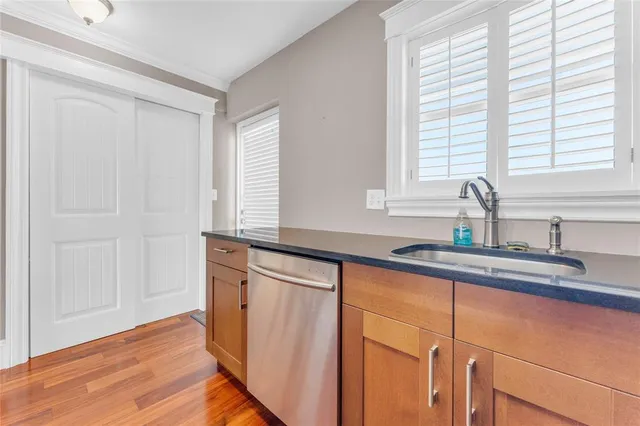 a kitchen with stainless steel appliances granite countertop a sink a window and wooden floor