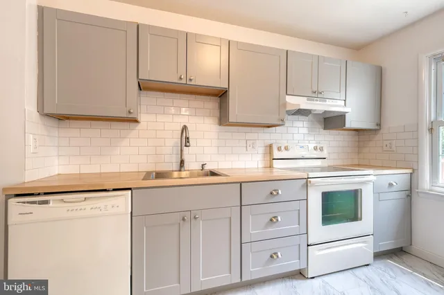 a kitchen with white cabinets white stainless steel appliances and sink