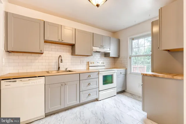 a kitchen with cabinets appliances a sink and a window