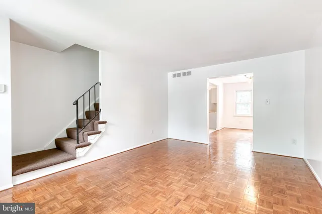 a view of an empty room with wooden floor and potted plants