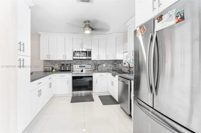a kitchen with stainless steel appliances cabinets a sink and a refrigerator