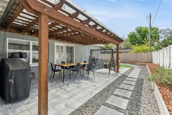 a view of a patio with table and chairs potted plants and floor to ceiling window