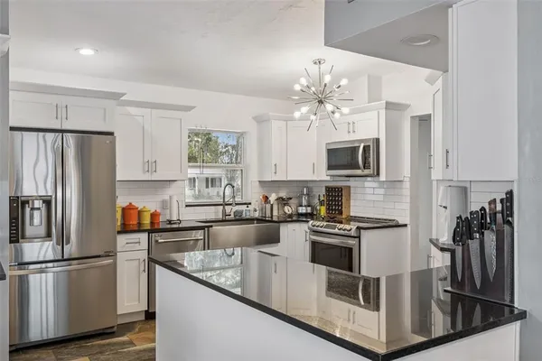 a kitchen with stainless steel appliances granite countertop a refrigerator a stove a microwave oven a sink with island and chairs