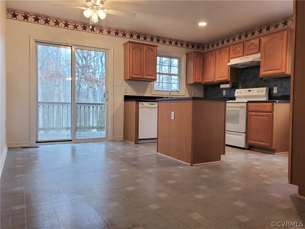 443 Lazy Acres Road Bumpass, VA 23024 - Photo 5 of 19 a kitchen with stainless steel appliances granite countertop a stove top oven a sink dishwasher a refrigerator and a dining table with wooden floor