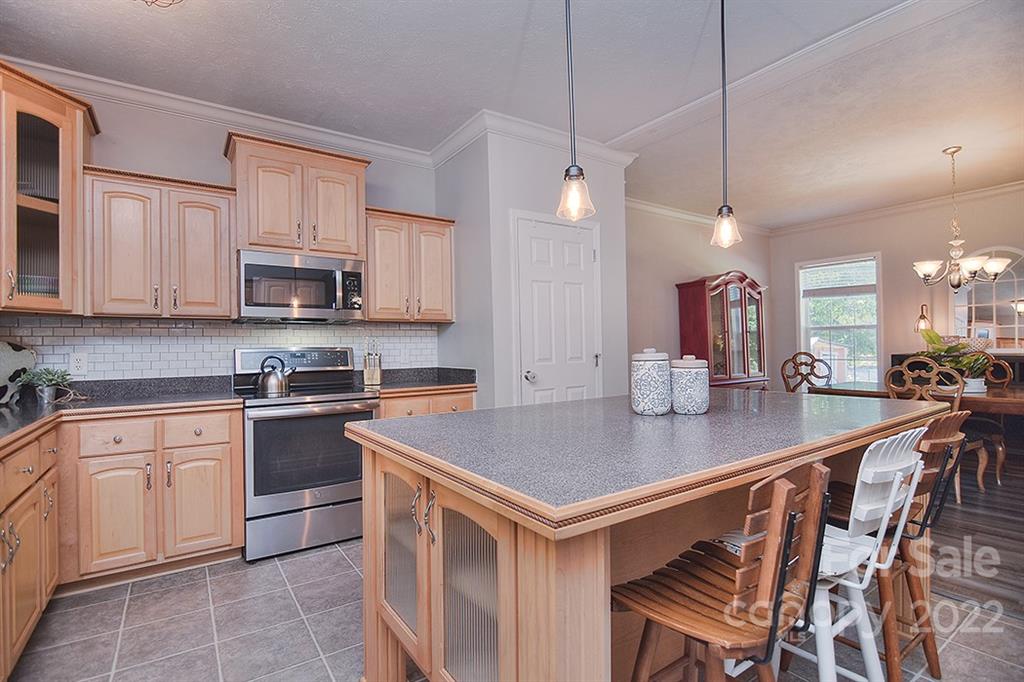 130 Printhad Road Dallas, NC 28034 - Photo 14 of 43 a kitchen with stainless steel appliances granite countertop a stove a sink a microwave a center island and chairs