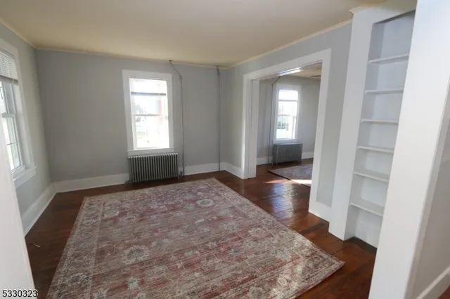 a view of empty room with wooden floor and window