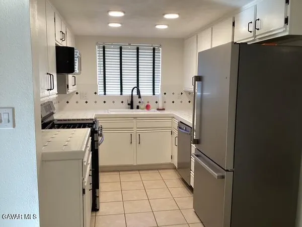 a kitchen with a sink a refrigerator and a stove top oven with wooden floor