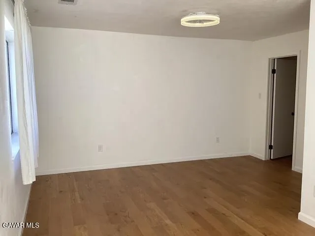 an empty room with wooden floor and bathroom