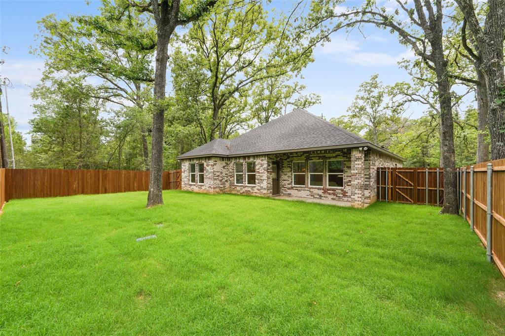 122 East Beachwood Loop Trinidad, TX 75163 - Photo 34 of 35 Expansive rear yard featuring a manicured lawn, full privacy fencing, and mature trees