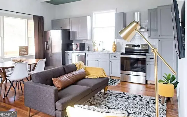 a kitchen with stainless steel appliances kitchen island granite countertop a refrigerator a stove a sink dishwasher a dining table and chairs with wooden floor