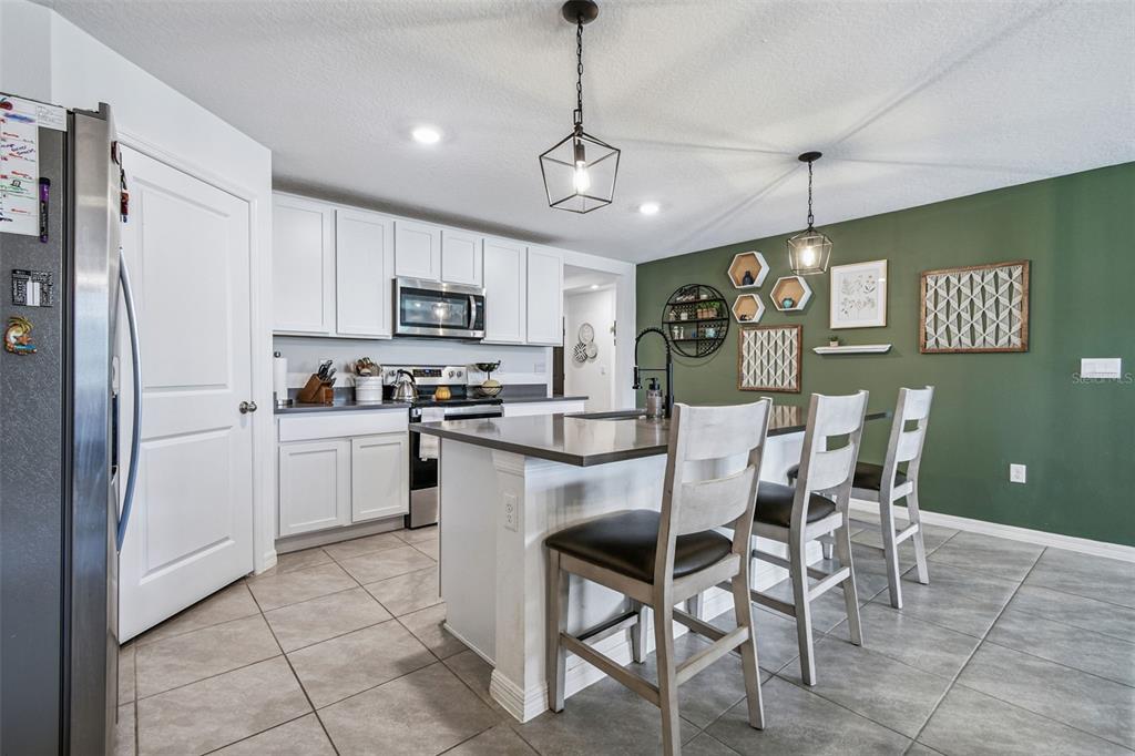 3139 Silver Date Drive Wimauma, FL 33598 - Photo 8 of 47 a kitchen with granite countertop stainless steel appliances a refrigerator oven a sink a stove a dining table and chairs