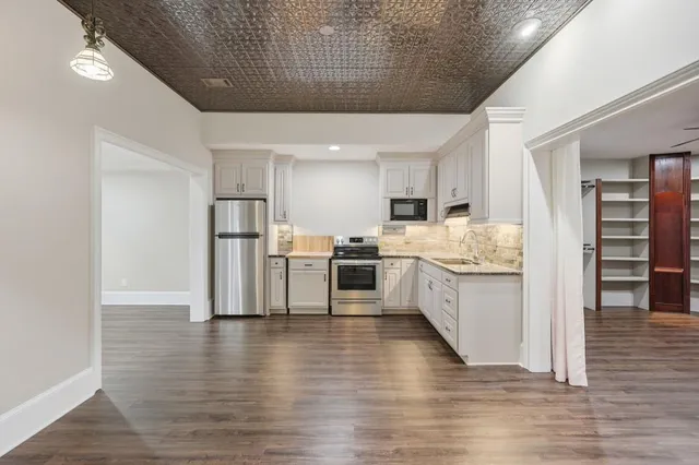 a large kitchen with cabinets wooden floor and stainless steel appliances