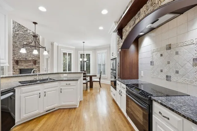 a large kitchen with stainless steel appliances granite countertop a lot of counter space and wooden floors