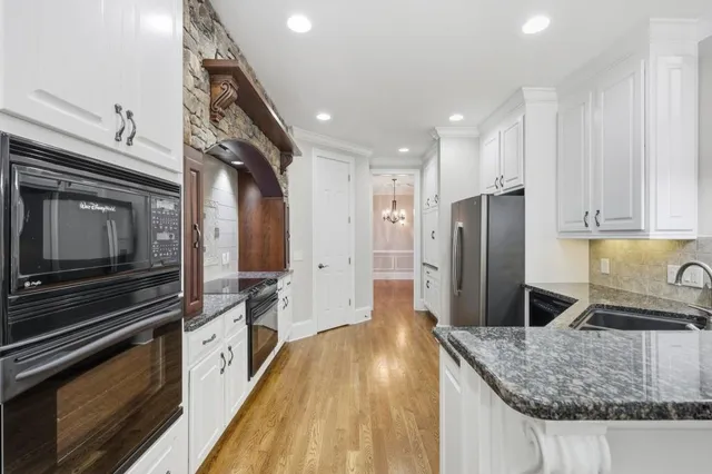 a kitchen with stainless steel appliances granite countertop a refrigerator a stove and a sink