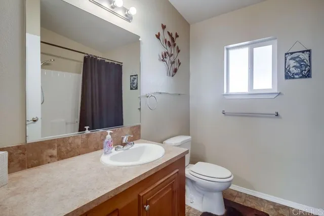 a bathroom with a granite countertop sink toilet and a mirror