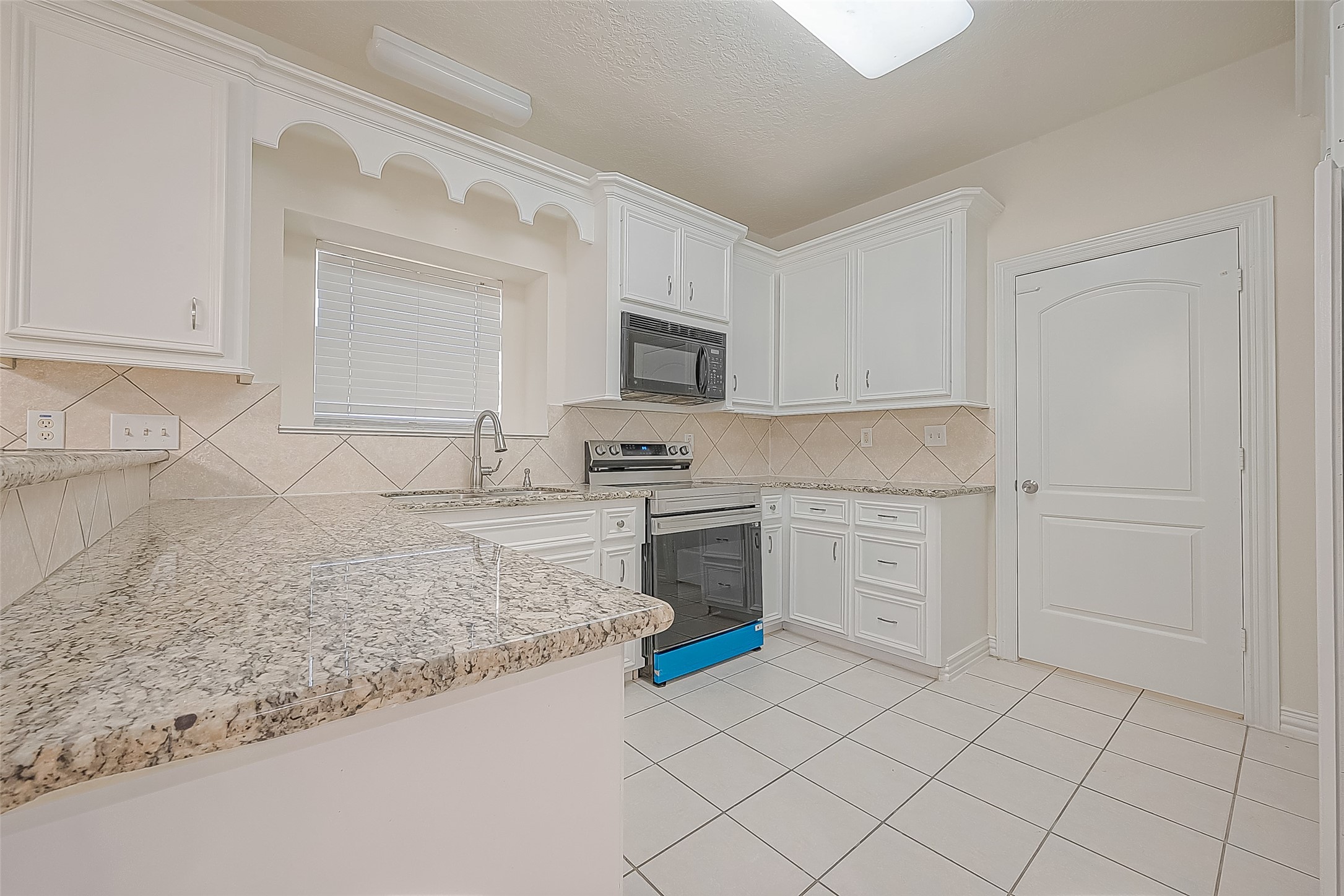 1189 Lovett Street Tomball, TX 77375 - Photo 19 of 36 a kitchen with granite countertop white cabinets and stainless steel appliances