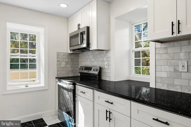 a kitchen with granite countertop a sink a window and stainless steel appliances