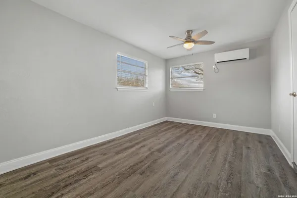 a view of an empty room with wooden floor and a ceiling fan