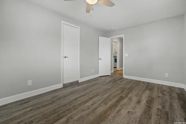 a view of an empty room with window and wooden floor