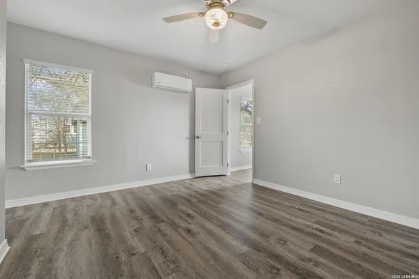 a view of an empty room with wooden floor and a window