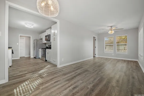 an empty room with wooden floor cabinet and windows