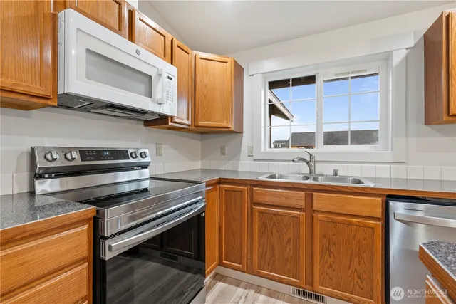 a kitchen with stainless steel appliances granite countertop a stove microwave and sink