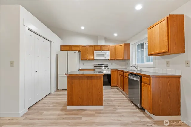 a large kitchen with stainless steel appliances granite countertop a stove a sink and a refrigerator