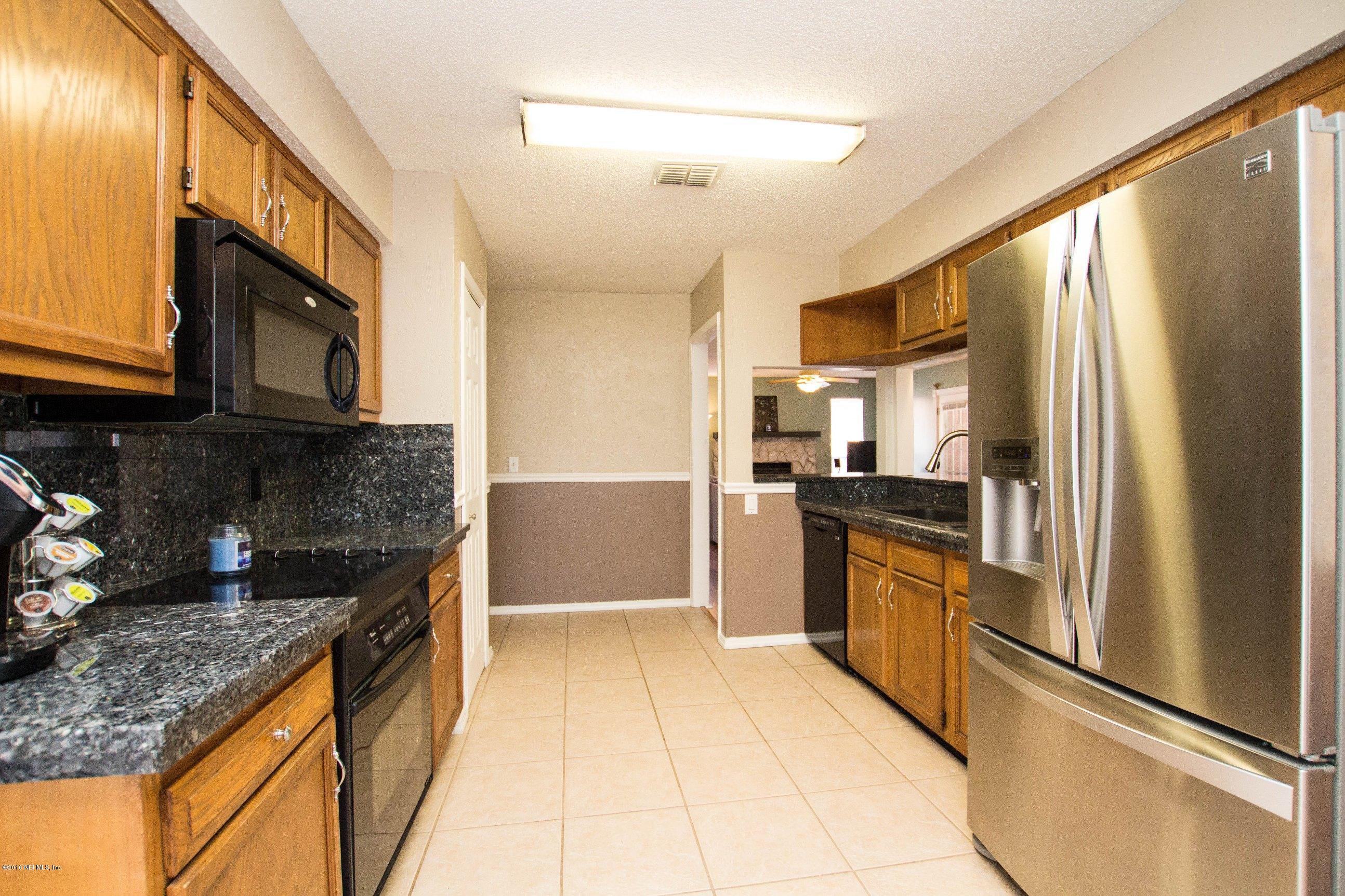 1609 Derringer Road Jacksonville, FL 32225 - Photo 18 of 33 a kitchen with stainless steel appliances granite countertop a refrigerator a stove and a sink with wooden cabinets