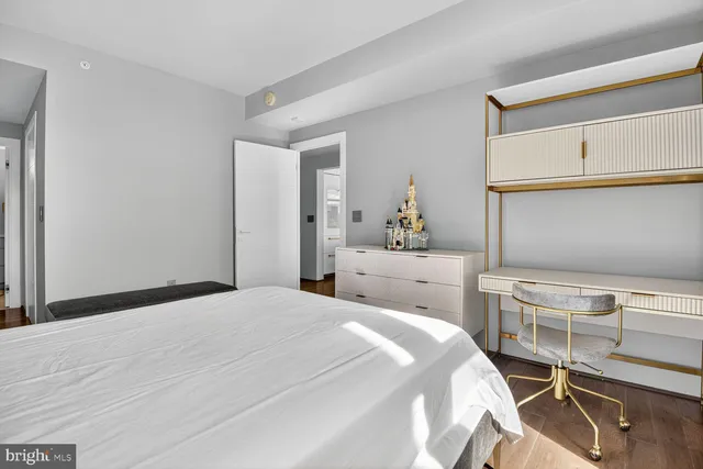 a view of a hallway with wooden floor and a bathroom
