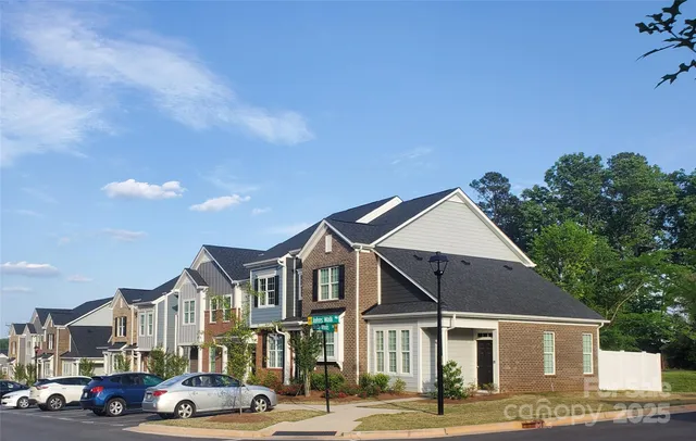 a front view of a building with lot of cars and trees