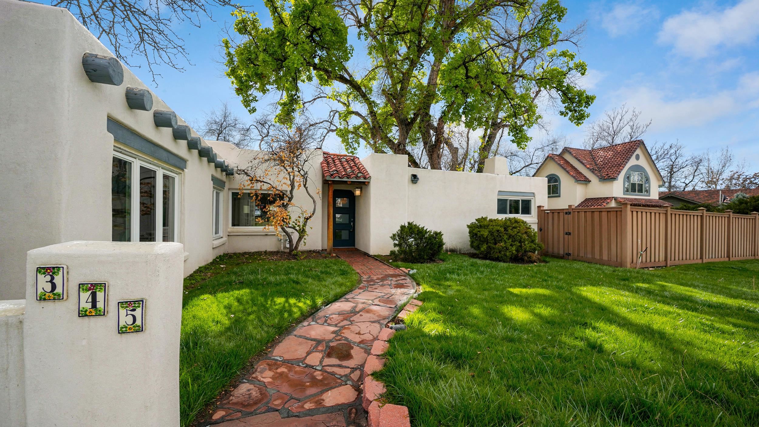 a view of a white house next to a yard with big trees
