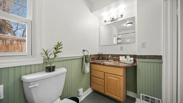 a bathroom with a granite countertop toilet sink and mirror