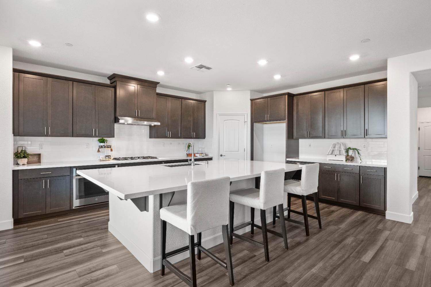 a kitchen with stainless steel appliances kitchen island granite countertop a table chairs sink and cabinets