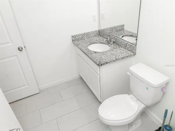 a bathroom with a granite countertop sink and a toilet