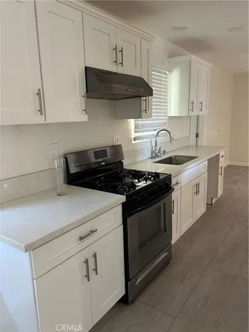 a kitchen with stainless steel appliances granite countertop white cabinets sink and stove