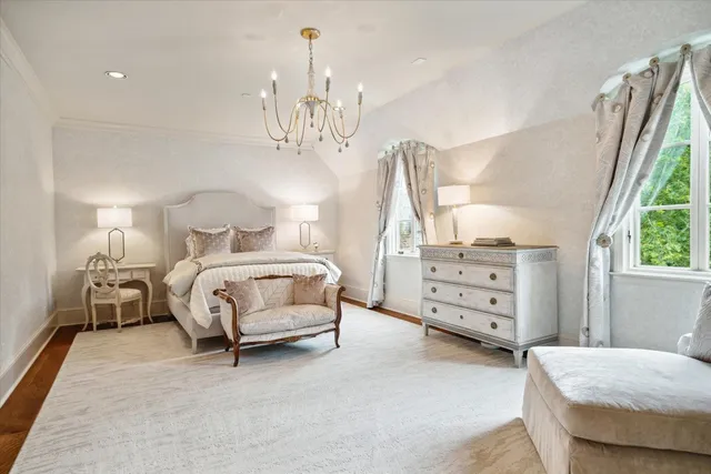 a bedroom with a bed chandelier and a window