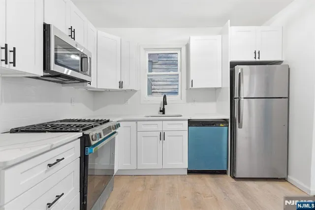 a kitchen with stainless steel appliances white cabinets and a refrigerator