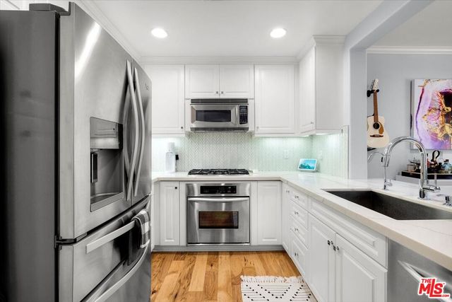 a kitchen with stainless steel appliances white cabinets and a stove top oven