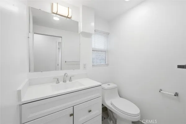 a bathroom with a toilet sink vanity and mirror