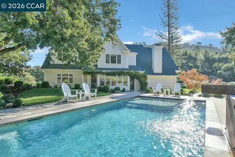 a view of a swimming pool and lounge chairs in back yard of the house
