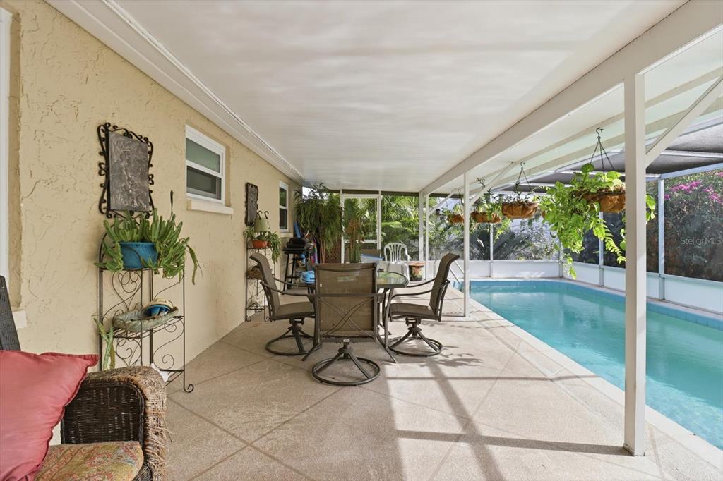 7410 Gulf Highlands Drive Port Richey, FL 34668 - Photo 36 of 45 a view of a patio with table and chairs potted plants with floor to ceiling window