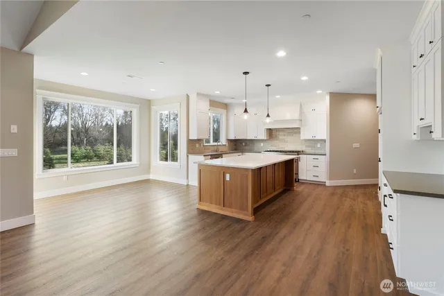 a large kitchen with a large counter top a sink stainless steel appliances and cabinets
