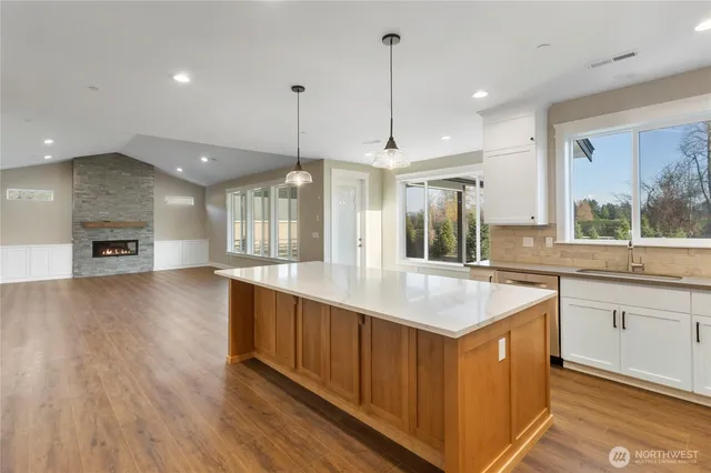 a kitchen with stainless steel appliances granite countertop a sink a stove and a wooden floor