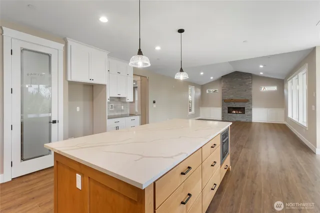 a large kitchen with kitchen island a stove a refrigerator a sink dishwasher with a dining table and chairs with wooden floor