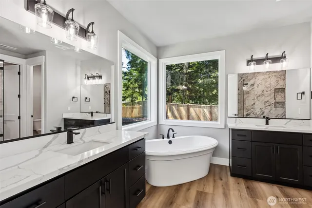 a bathroom with a double vanity sink a large mirror and a bathtub